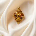 “DivyGold 1 gram gold-plated ornate floral shield ring on cream fabric background”