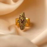 “DivyGold 1 gram gold-polished marquise temple ring with red stone accents on cream satin”