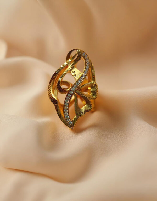 "DivyGold designer imitation ring with 1 gram gold polish and sparkling crystals on peach fabric background"