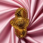"DivyGold traditional ethnic ring with 1 gram gold polish and red enamel design placed on pink satin fabric"